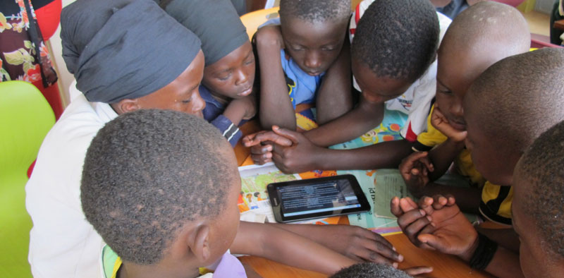 Children in Kenya's slum Kibera reading something on their tablet