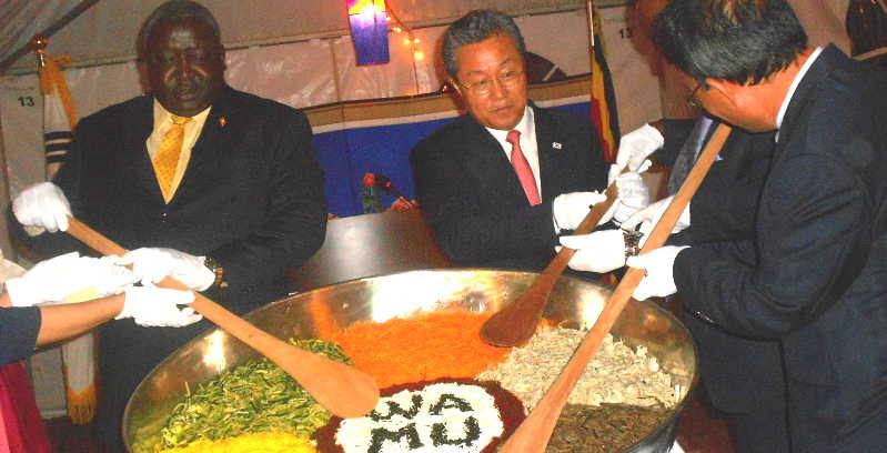 Foreign Affairs Minister Henry Oryem, Left, with Amb. Park and other Korean officials mingle Korean rice decorated WAMU which is Luganda term to mean 'Together'