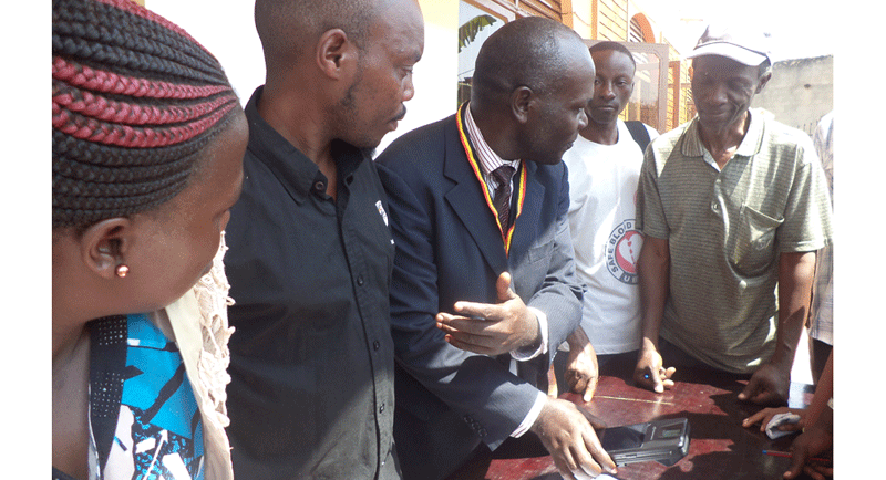 EC Kawempe Division Sserunjogi Vicent demonstrating to voters how the biometric verification system works in Kawempe