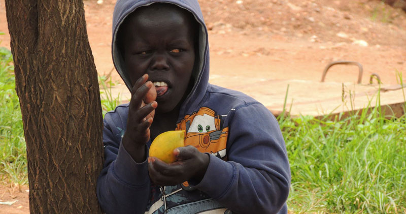 A street child eating a mango
