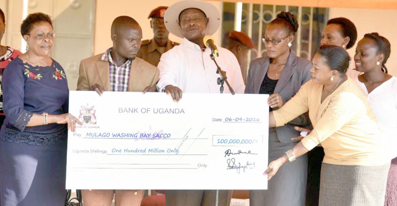 President Museveni handing over a dummy check to members of Mulago SACCO which was not registered by the time they got the money