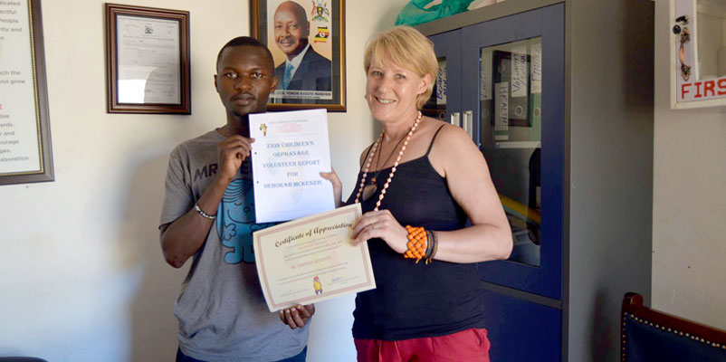 Director and founder Alex Ssebakiwa handing Deborah McKenzie a certificate of appreciation at the ZCO head offices in Makindye 