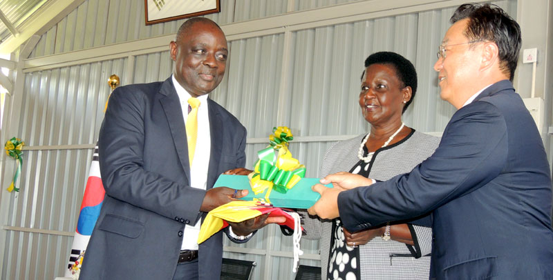 South Korean Envoy Park Jongdae hands over keys to the leadership centre to Agriculture Minister Vicent Ssempijja while area MP and Trade Minister Amelia Kyambadde looks on