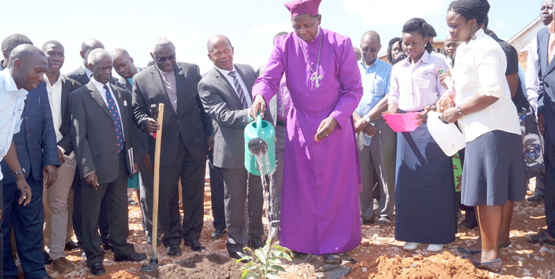 Archibishop Ntagali and Edication minister JC Muyingo planting a tree. Holding the hoe is vice chancellor Dr. John Ssenyonyi