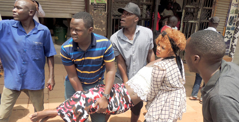 Business people helping a woman who fainted after gun shoots rocked Kampala 