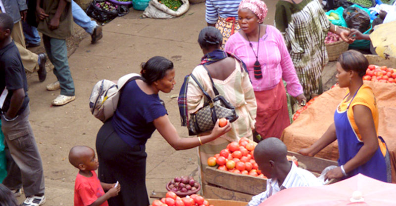A woman buys tomatoes from a roadside vendor