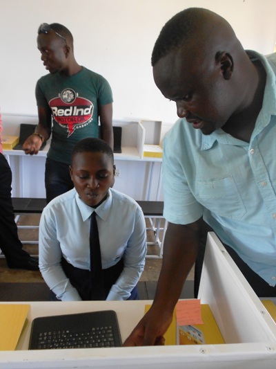 Virtual Learn Project Manager Ivan Mukasa Ssensalire shows a student how the systems works