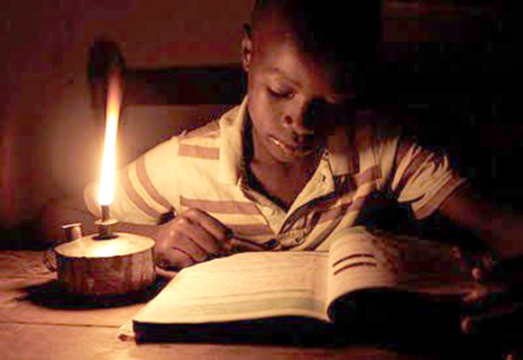 A child struggles to read on a "tadooba" (Kerosene lamp)