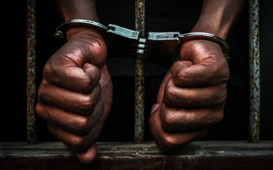 18-11-07-African-man-handcuffed-in-jail-stock-photo-min