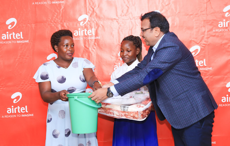 Airtel Uganda Networks Director, Mr. Agarwal,(L ), handing over a Secondary School Start-Up Kit to one of the 14 top-performing pupils in four of Airtel Uganda's adopted schools in the recently released Primary Leaving Examinations (PLE) results